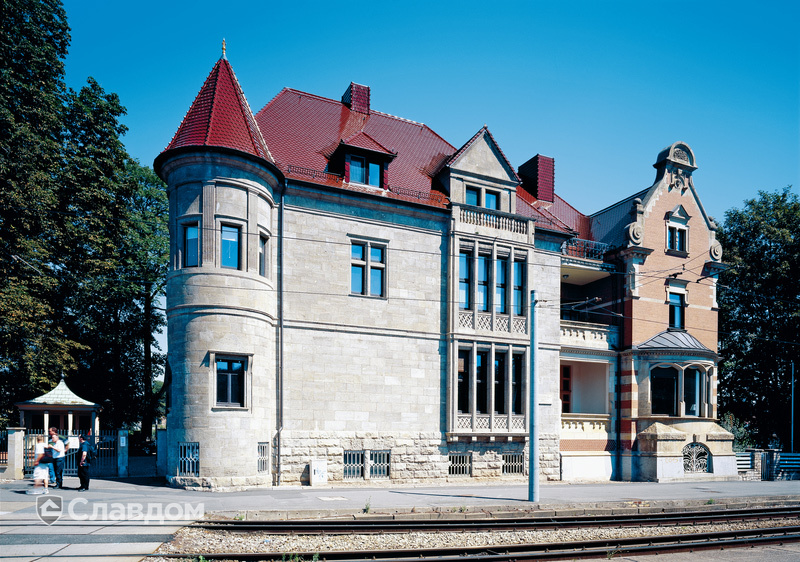 Здание с оригинальным фасадом и крышей из черепицы Creaton Biber Klassik Braun Glasiert.